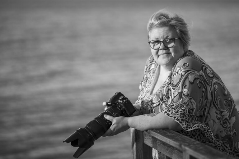 Kvinna står vid brygga med kamera i handen svartvit bild