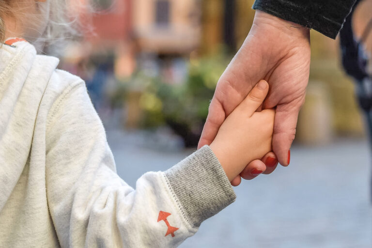 En vuxen och ett barns händer håller hand.